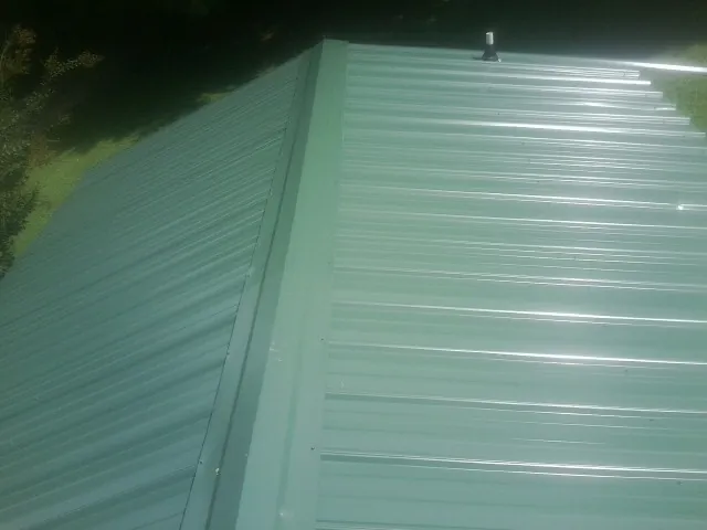 New green metal panels meeting at the ridge of a roof — Flat Roof Repair work by our crew in Wallingford