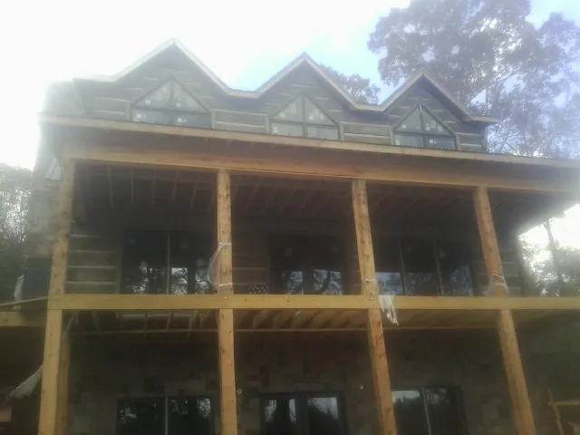 Dormers and porch framing on a large log home under construction — Roof Coating work by our crew in Wallingford