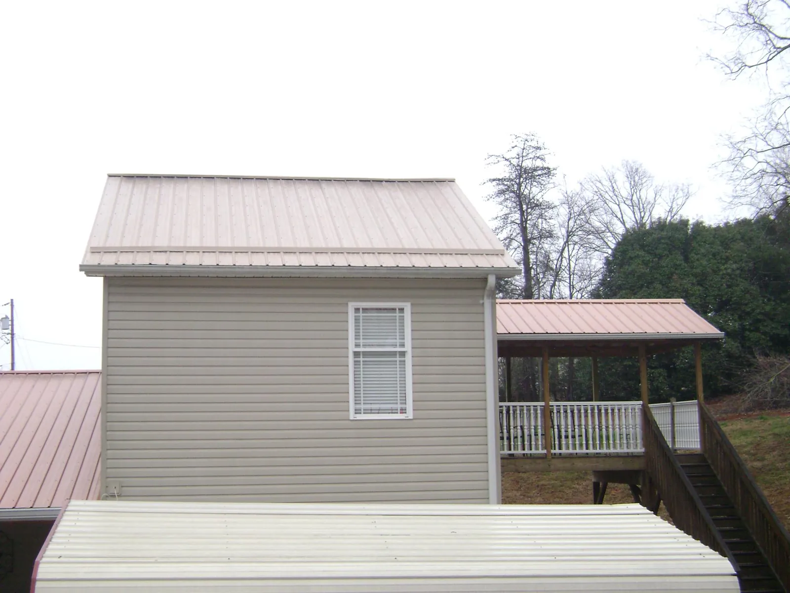 Tan metal roofs on a two story addition and attached porch, from a Roof Replacement job in Wallingford